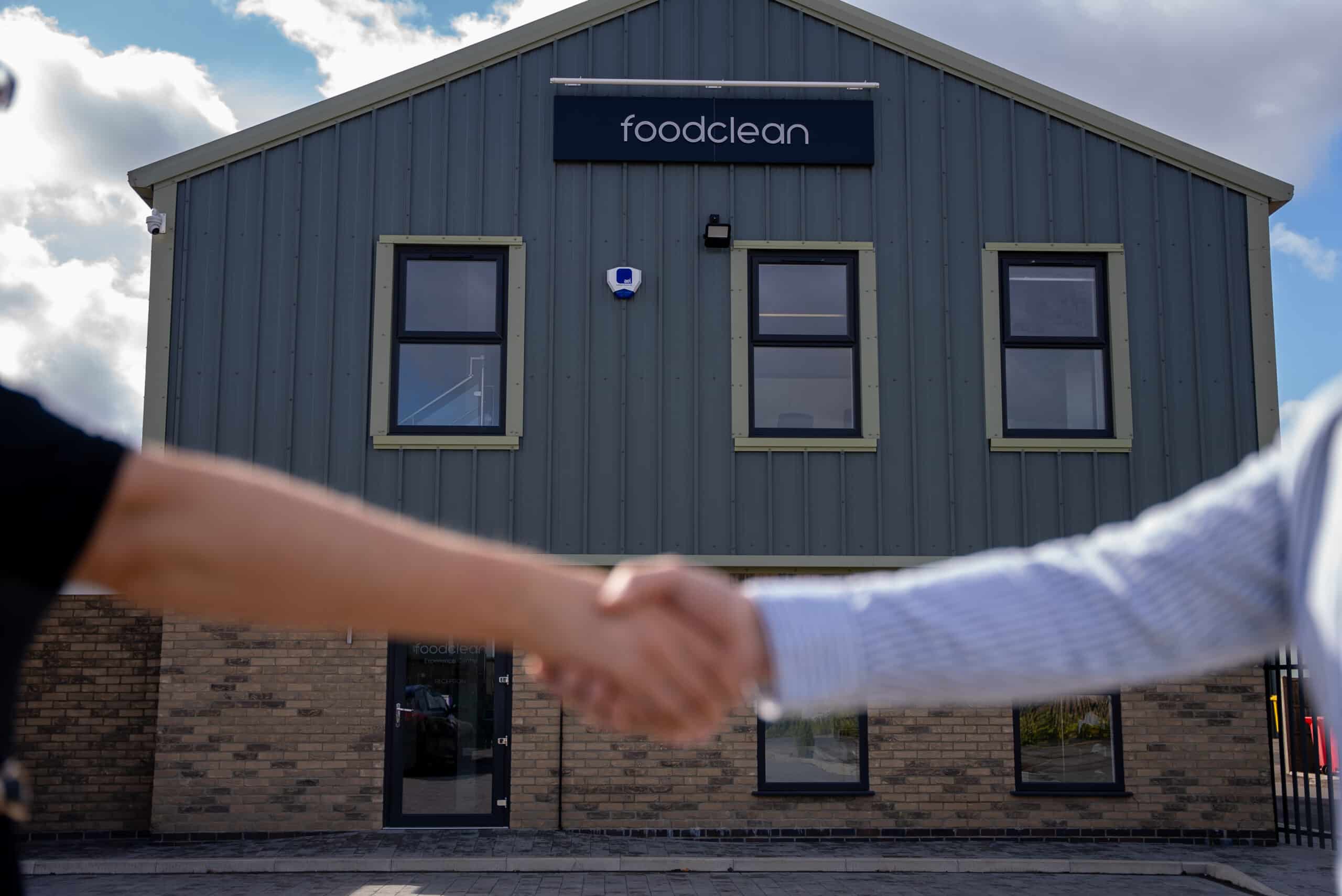 FoodClean building with 2 people shaking hands in front of it