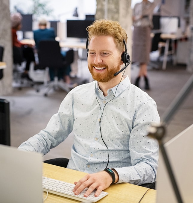 Smiling customer service representative with a headset working at a computer in Foodclean's modern open-plan office.